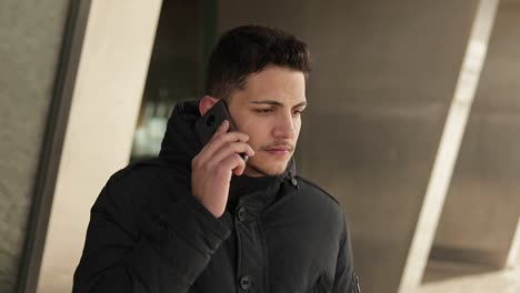 Upset-young-man-talking-on-phone-outdoor